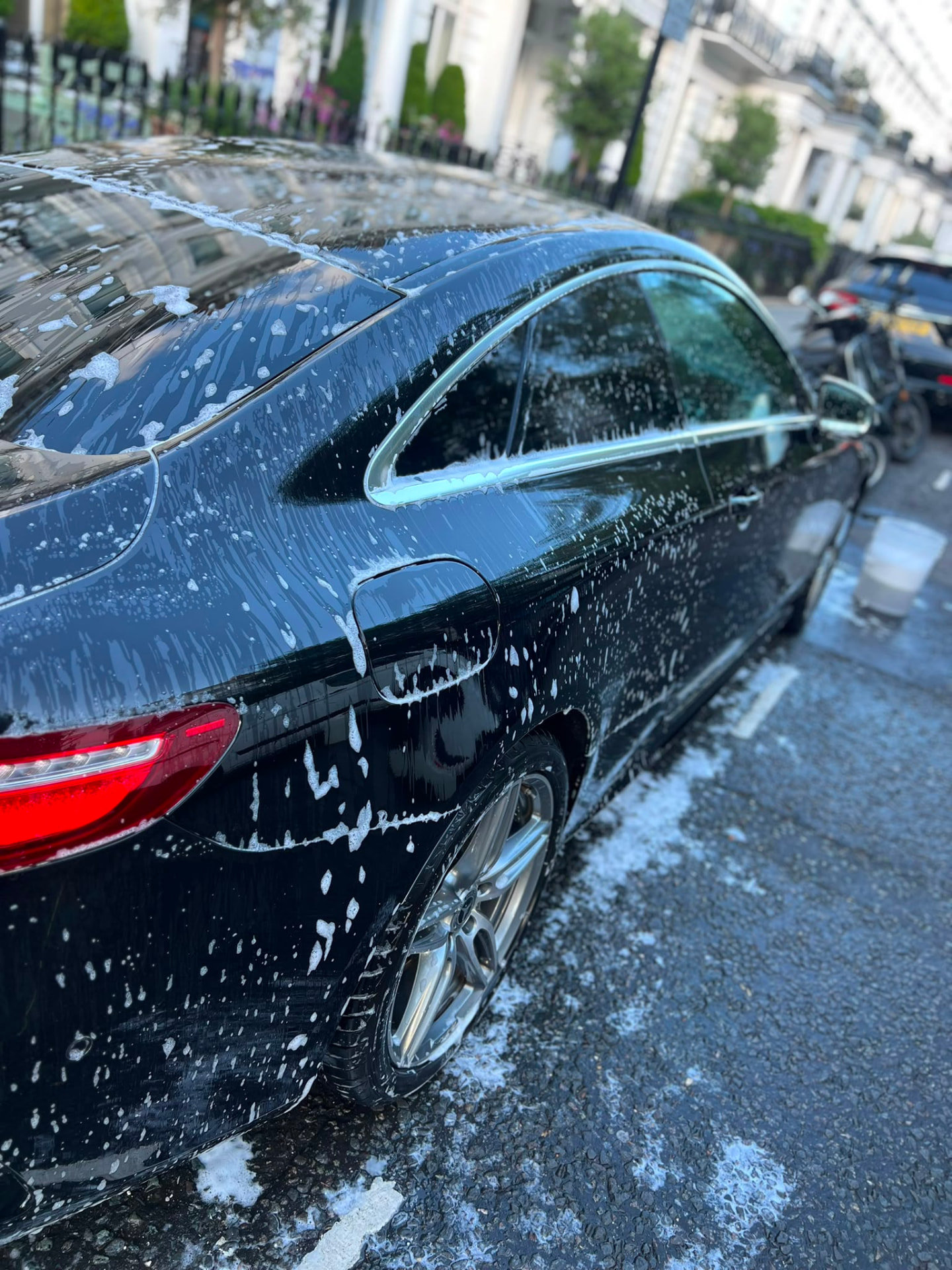 Snow foam covering a black Mercedes coupe during a mobile wash